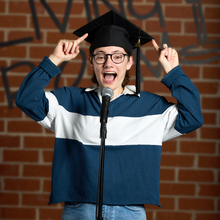 Male Student Smiling and Pointing at Mortarboard Graduation Cap