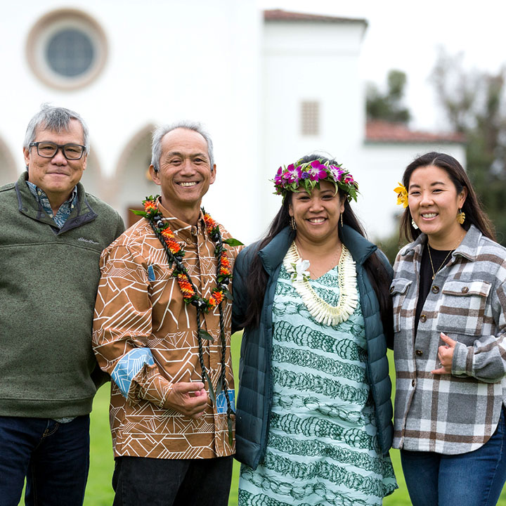 Four API alumni in front of Sacred Heart Chapel