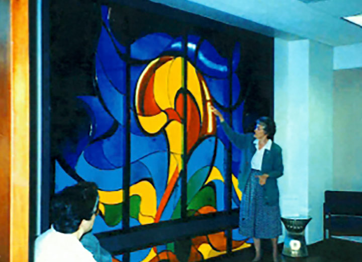 Genevieve Underwood, R.S.H.M. with a stained-glass window she created.