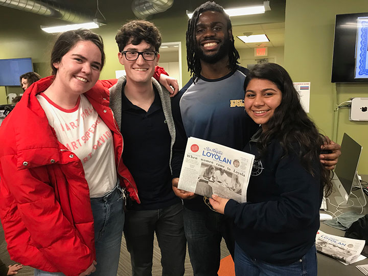 Four scholarship recipients holding an issue of The Loyolan